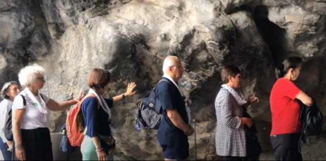 Peregrinos en la gruta de Massabielle en el santuario de Lourdes
